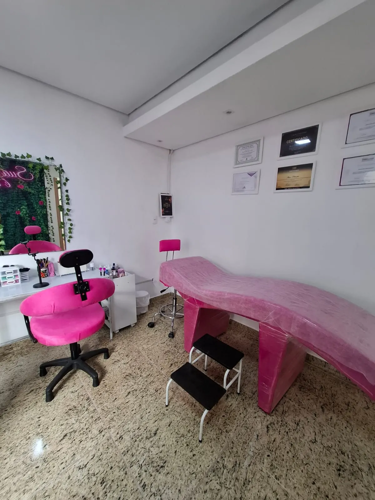 Espaço de atendimento do Thais Mendes Studio, com cadeira e maca em tons de rosa
